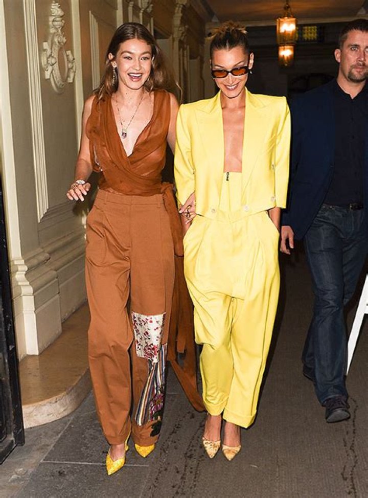 Gigi & Bella Hadid Are Twinning In Plunging Pantsuits At The ‘Americans In Paris’ Event In France